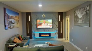 A modern living room with a flat-screen TV, a fireplace, and artwork on the walls.