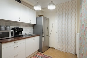A compact kitchen with white cabinets, a stainless steel refrigerator, a coffee maker, and a microwave.