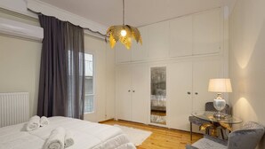 Ein Hotelzimmer mit Bett, Stuhl, Tisch mit Lampe und Schrank.