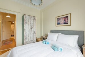 A bedroom with a large bed, a wardrobe, and a painting on the wall.
