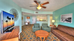 A living room with a TV, sofa, chairs, and a ceiling fan.