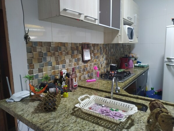 Una cocina con salpicadero de azulejos, encimera de granito y diversos electrodomésticos.