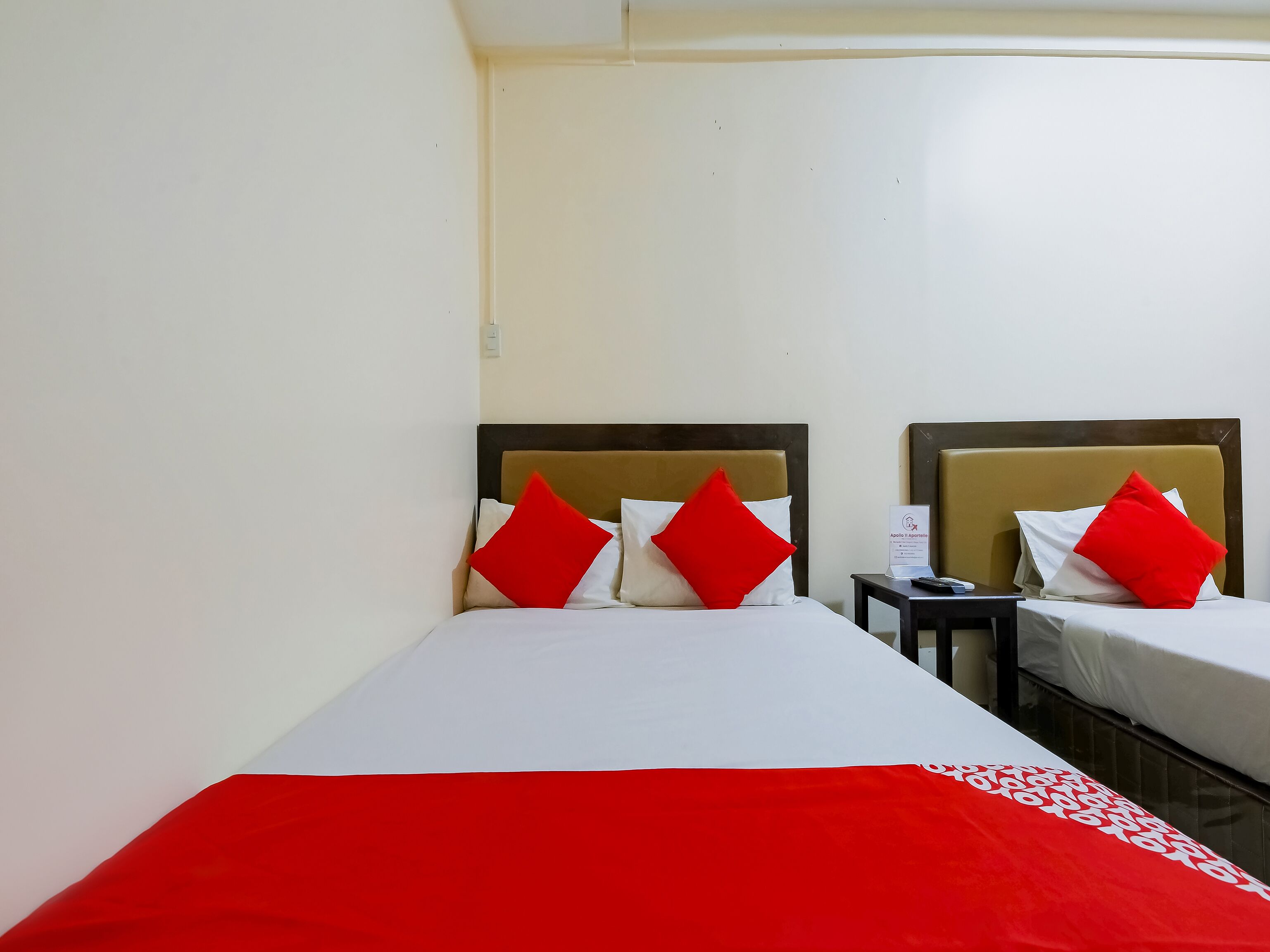 A hotel room with two beds, each with a headboard, and a nightstand between them.