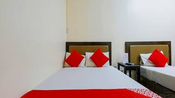 A hotel room with two beds, each with a headboard, and a nightstand between them.