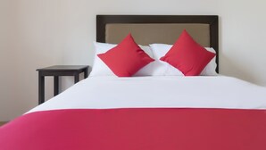 A bed with a white and red bedspread, two red pillows, and a wooden headboard. - OYO 431 Apollo 11 Apartelle (Pasay)
