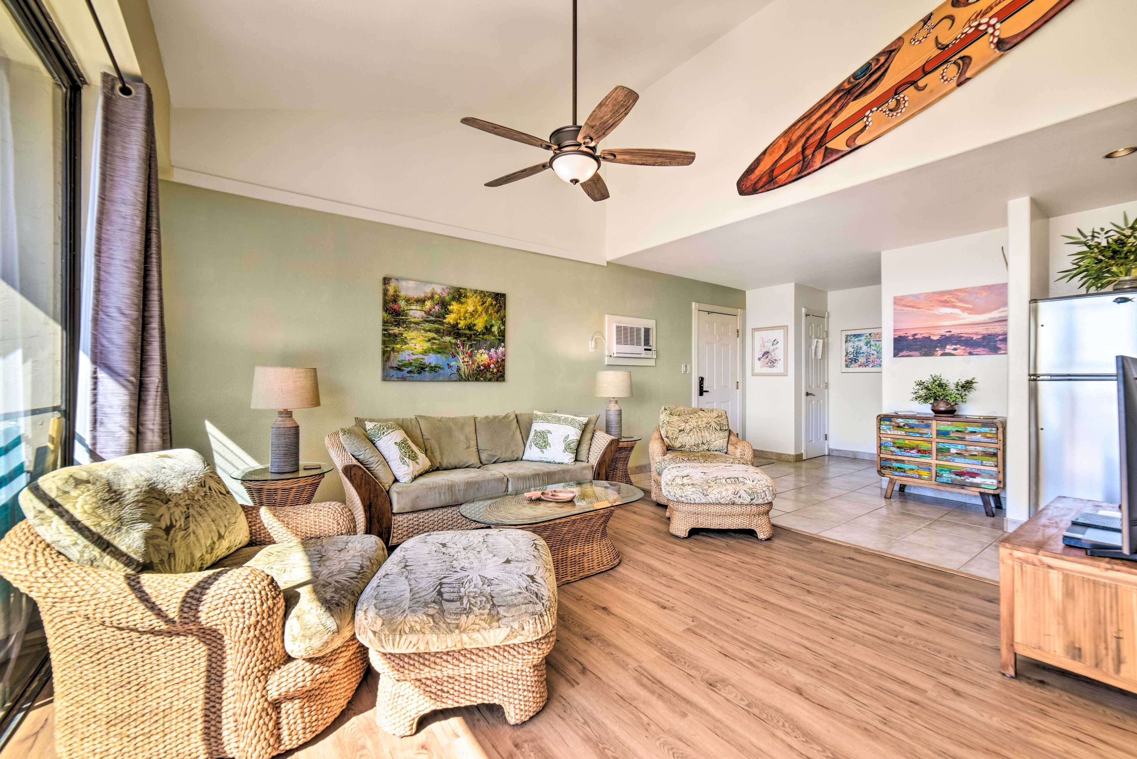 A spacious living room with a sofa set, ottomans, a coffee table, and a ceiling fan.