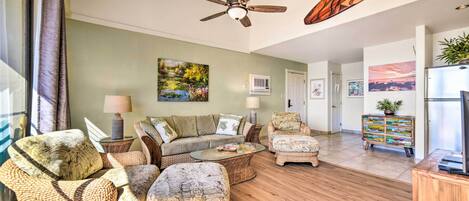 A spacious living room with a sofa set, ottomans, a coffee table, and a ceiling fan.