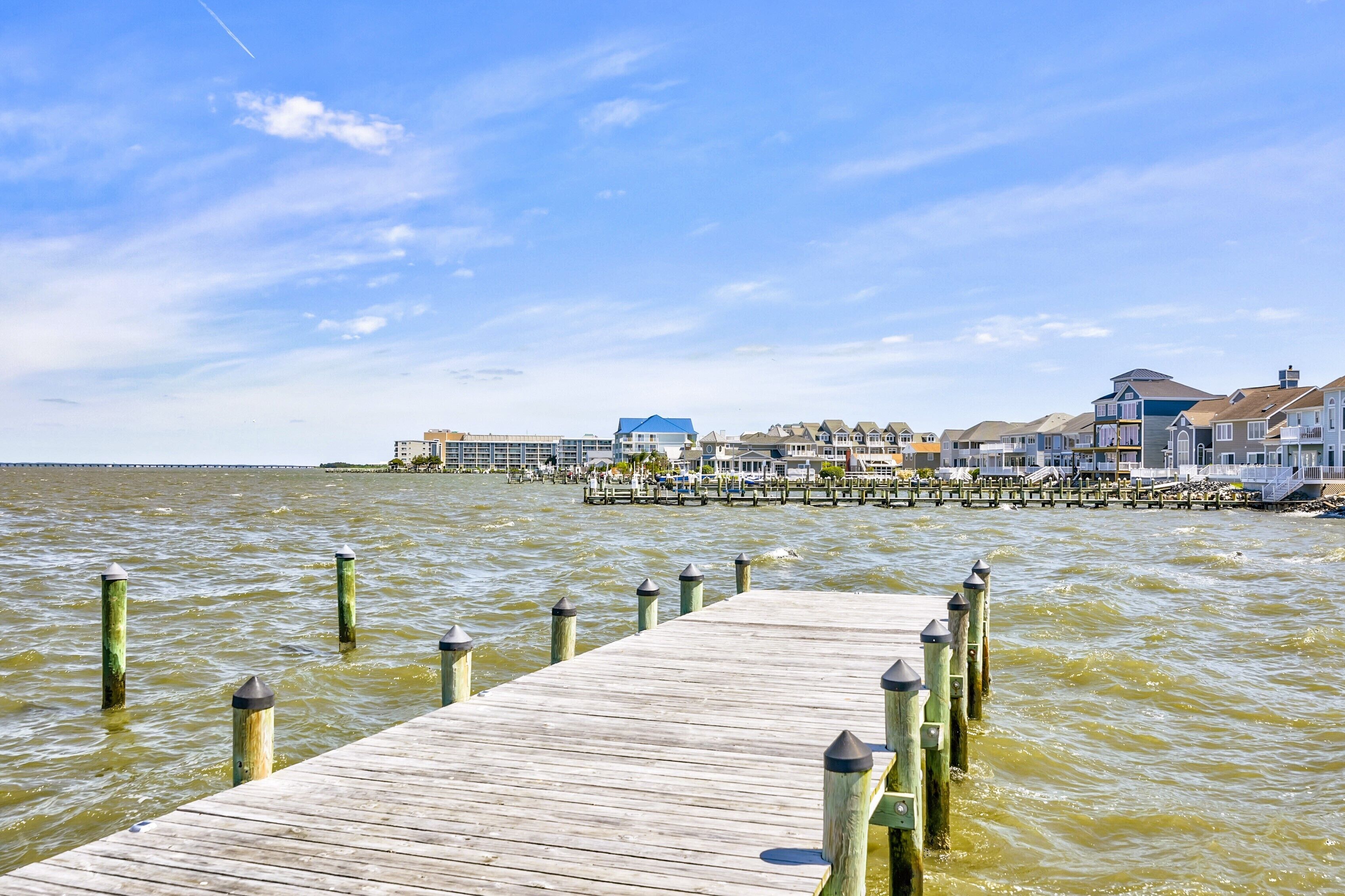A wooden pier leading to a waterfront area with buildings and a dock.