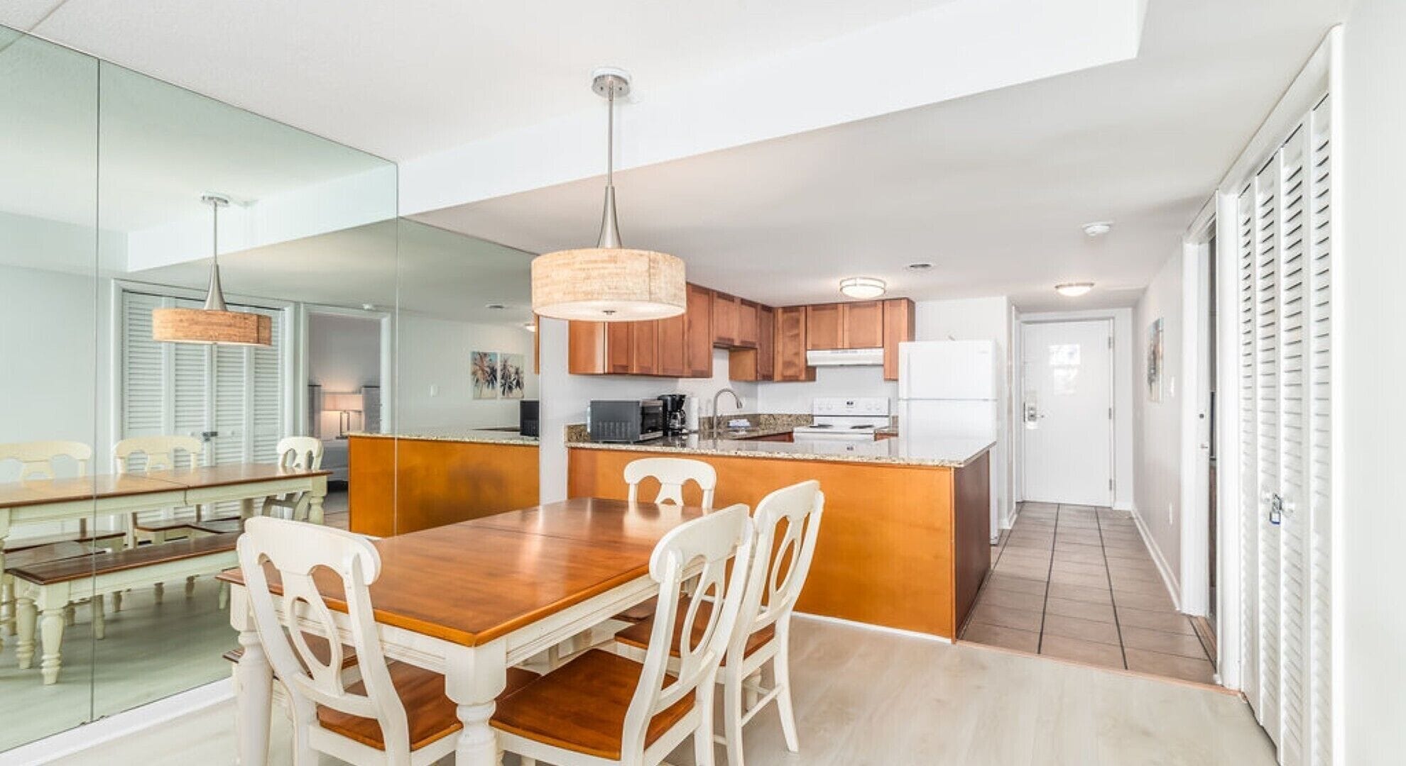 A modern kitchen with wooden cabinets, a central island, and a dining area with a wooden table and white chairs.
