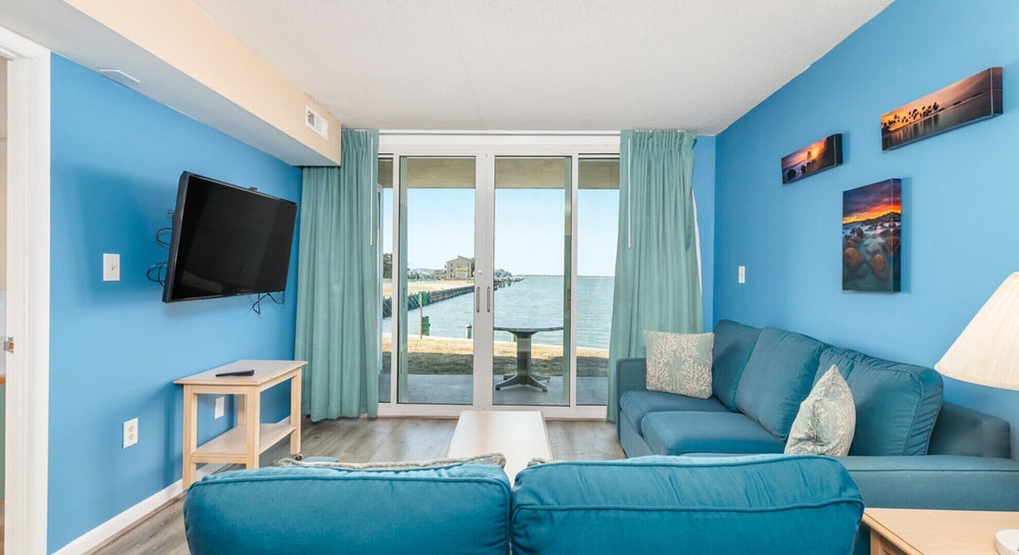 Una stanza con una parete blu, una televisione, un divano e vista sul mare.