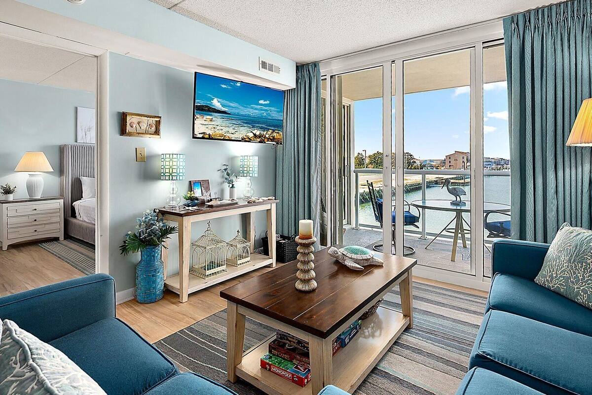 Ein Wohnzimmer mit Blick auf das Wasser, einem Holztisch, einer Couch und einem Fernseher.