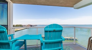 A balcony with turquoise Adirondack chairs and a view of the water.