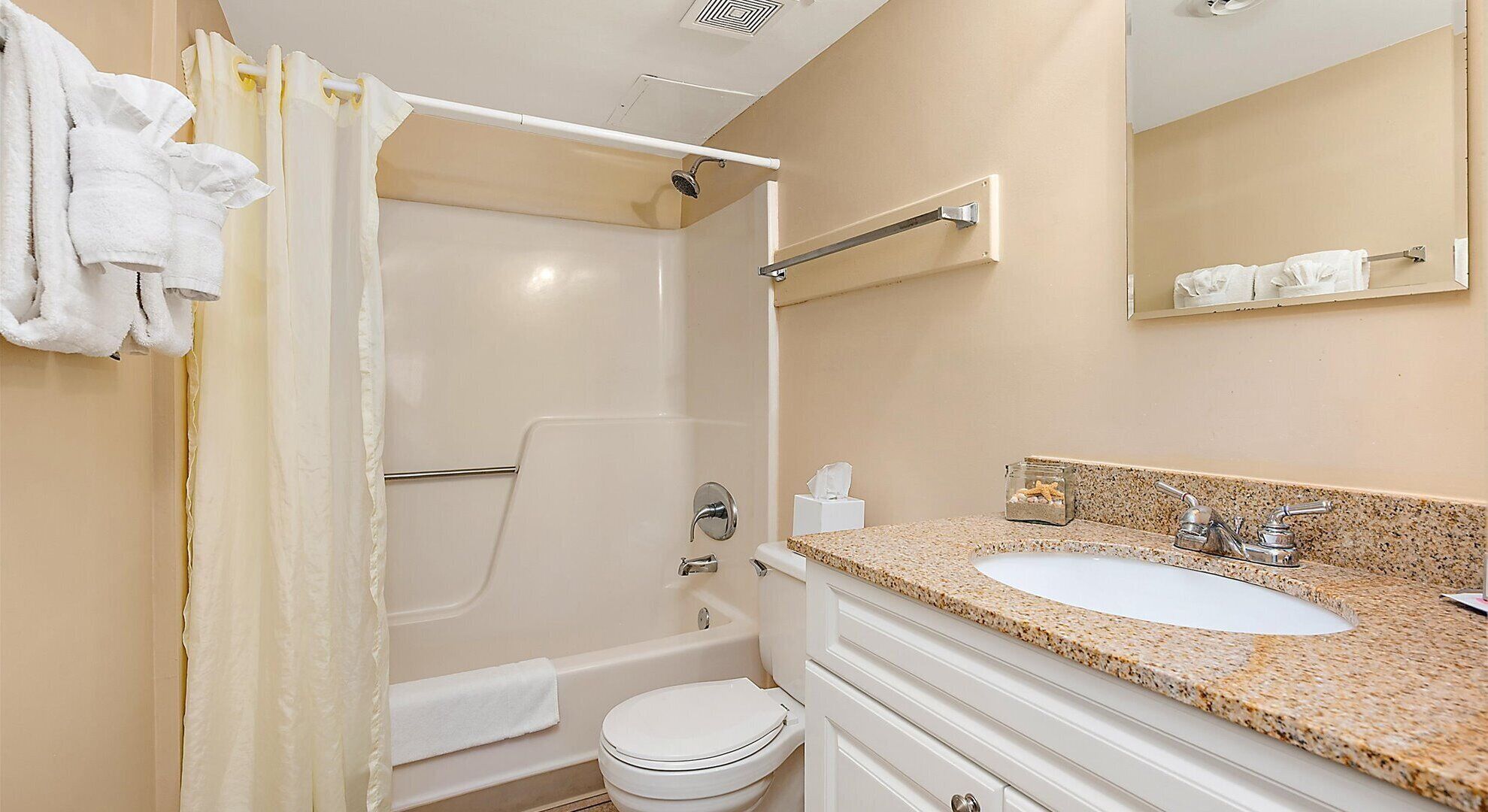 A bathroom with a shower, toilet, sink, and a towel rack.
