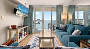 Un salon moderne doté d’un grand téléviseur, d’un canapé, d’une table basse et offrant une vue sur la mer.
