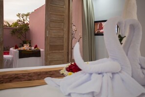 Relax in a cozy space with a neatly arranged bed, dining area, and mounted TV.