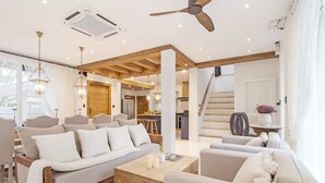 Uma sala de estar moderna com sofá, mesa de centro e cadeiras, integrada a uma cozinha e área de jantar.