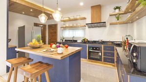 Uma cozinha moderna com ilha central, banquetas de madeira e eletrodomésticos embutidos.