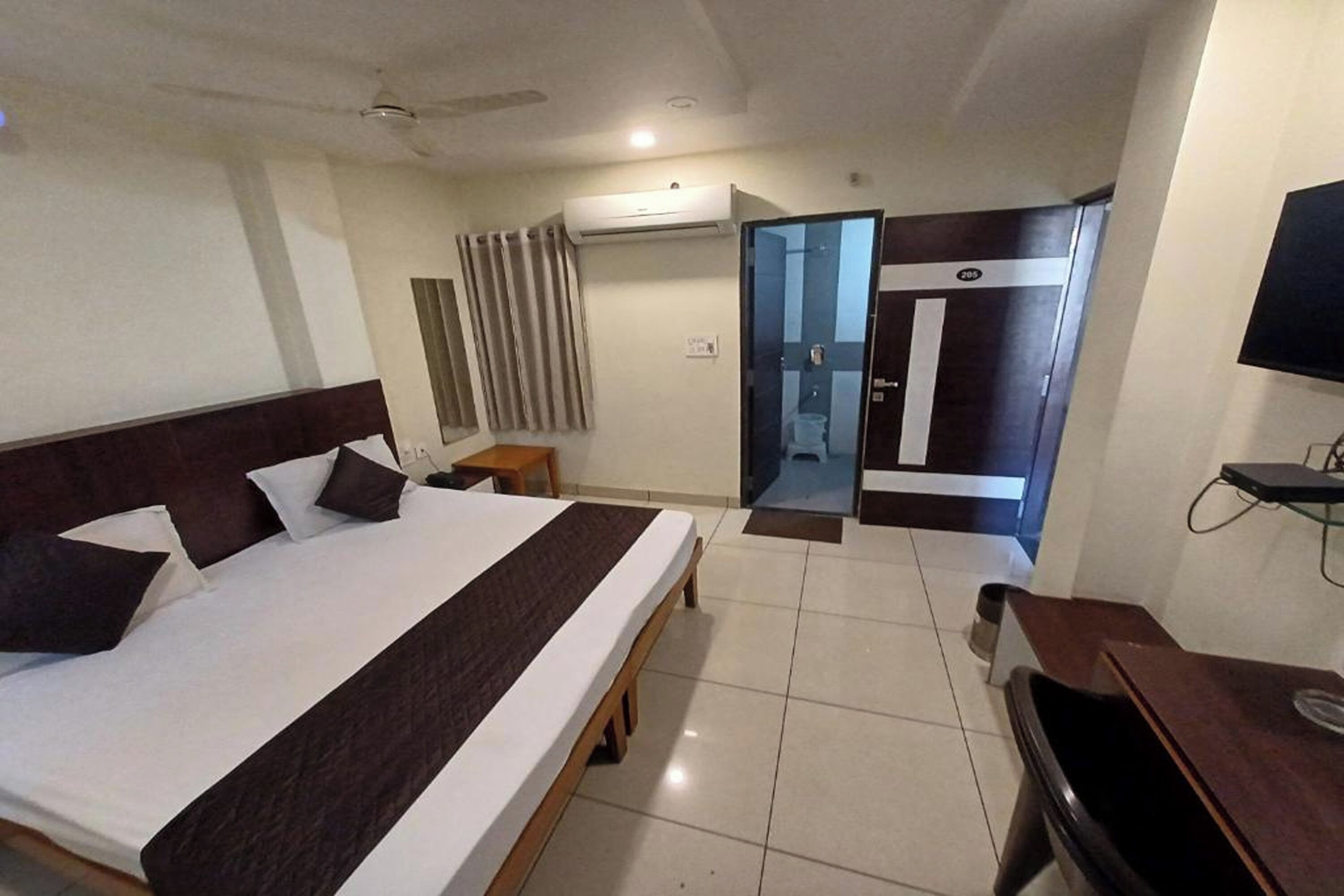 Une chambre d’hôtel équipée d’un lit, d’un bureau, d’une télévision, d’un système de climatisation et d’une salle de bain avec douche et toilettes.