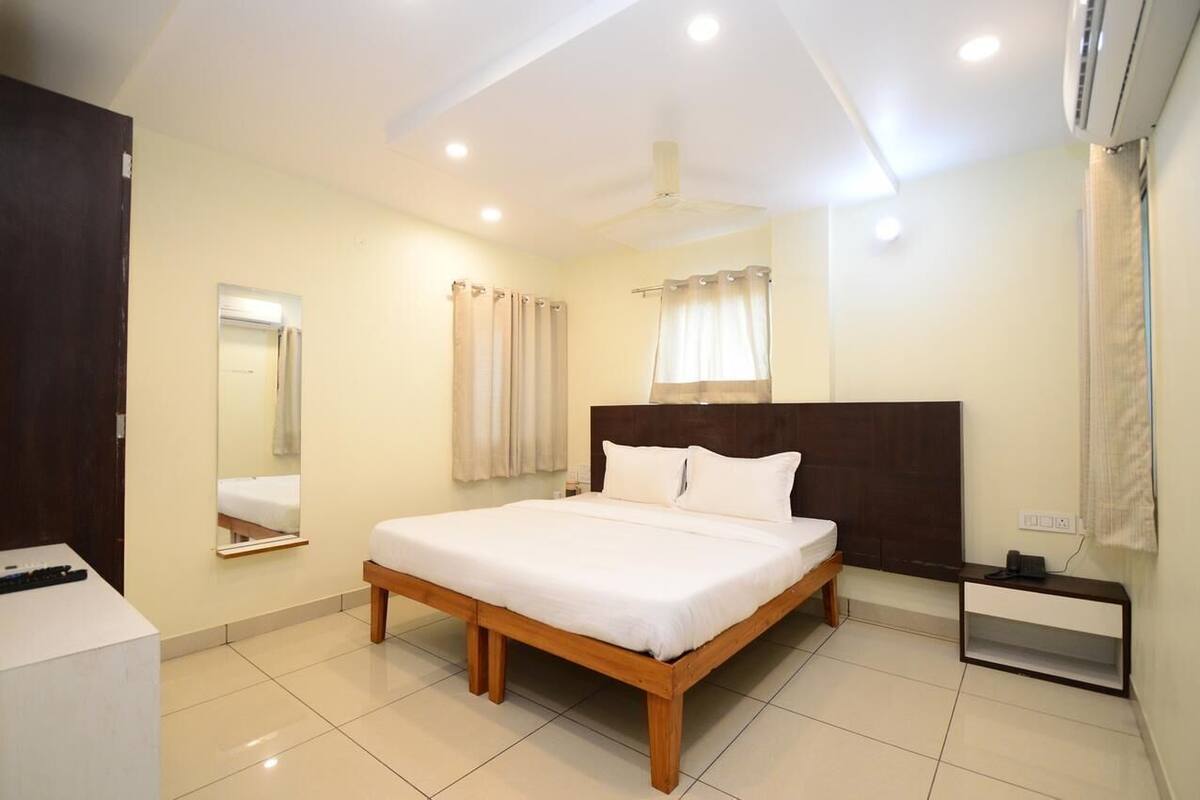 A bedroom with a bed, a bedside table, a mirror, a ceiling fan, and an air conditioning unit.