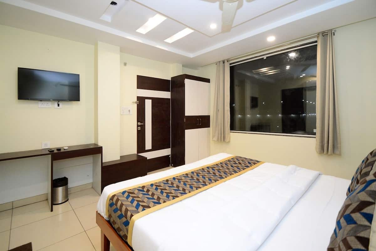 A hotel room with a bed, a TV, a desk, and a wardrobe.