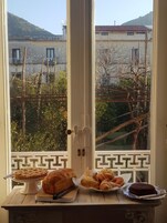 Una ventana con vistas a una zona residencial, una mesa con pasteles y un pastel en un soporte.