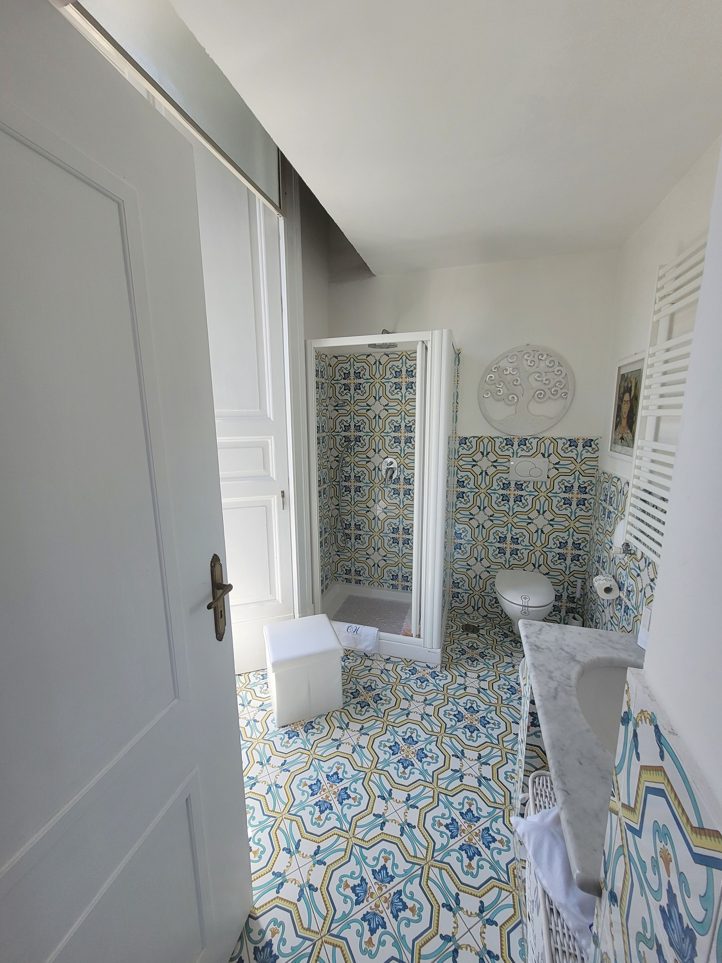 Uma casa de banho com azulejos estampados, chuveiro, sanita e banheira.