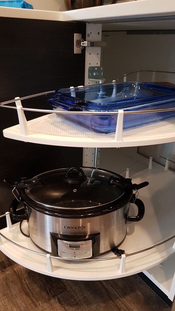 A kitchen with a stainless steel Crock-Pot on a white countertop, a blue glass baking dish on a white rack, and a white oven door.