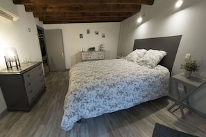A bedroom with a bed, dresser, nightstand, and a small table with a plant. - "Chez Mémé Caillou" cottage 6 people (Montmirail)