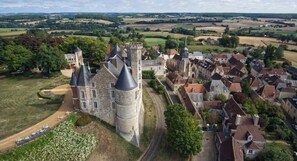 Oversigtsbillede af et historisk slot med voldgrav, omgivet af en landsby med traditionel arkitektur.