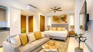 A modern bedroom with a bed, a sofa, a ceiling fan, and a TV mounted on the wall. - Romantic Zone Gem | 2 Pools, Gym | Walk to Beach (Puerto Vallarta)