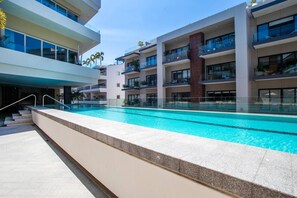A modern hotel with a swimming pool, multiple balconies, and a clear sky. - Romantic Zone Gem | 2 Pools, Gym | Walk to Beach (Puerto Vallarta)