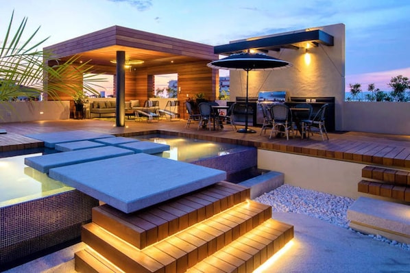 A modern outdoor pool area with built-in seating and a barbecue setup.