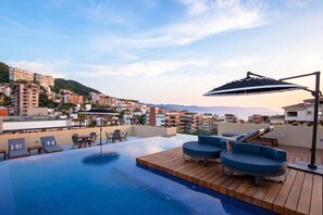 Et tagområde med swimmingpool, liggestole og en pergola.