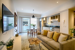 A modern living room with a sofa, coffee table, and dining area.