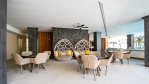 A modern lounge area with round seating, a ceiling fan, and a view of the outdoors. - Romantic Zone Gem | 2 Pools, Gym | Walk to Beach (Puerto Vallarta)