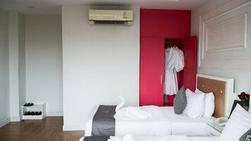 A hotel room with a bed, a bedside table with a phone, a shoe rack, and a red wardrobe.