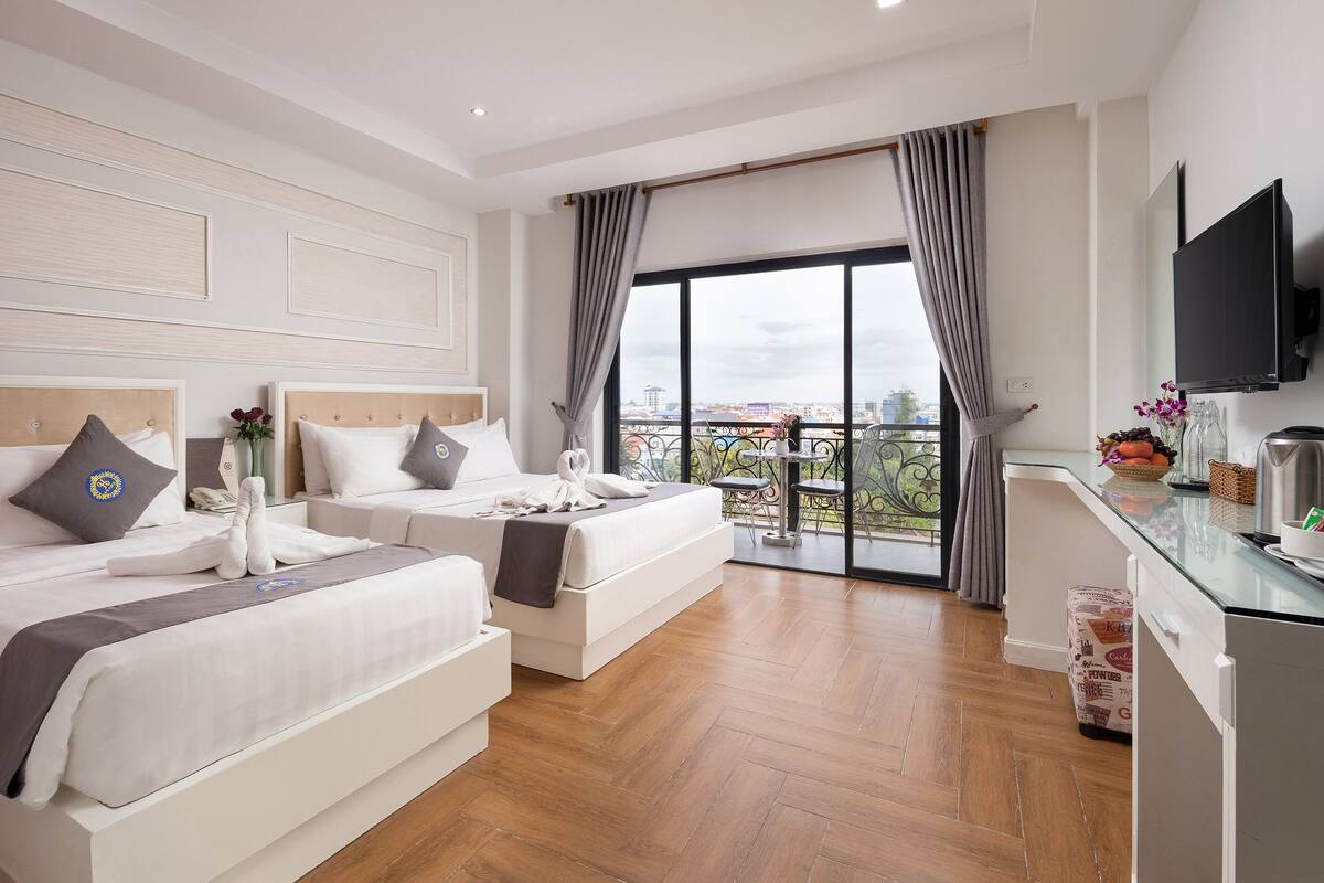 Ein Hotelzimmer mit zwei Betten, einem Balkon mit Blick auf die Stadt und einer Küchenzeile.
