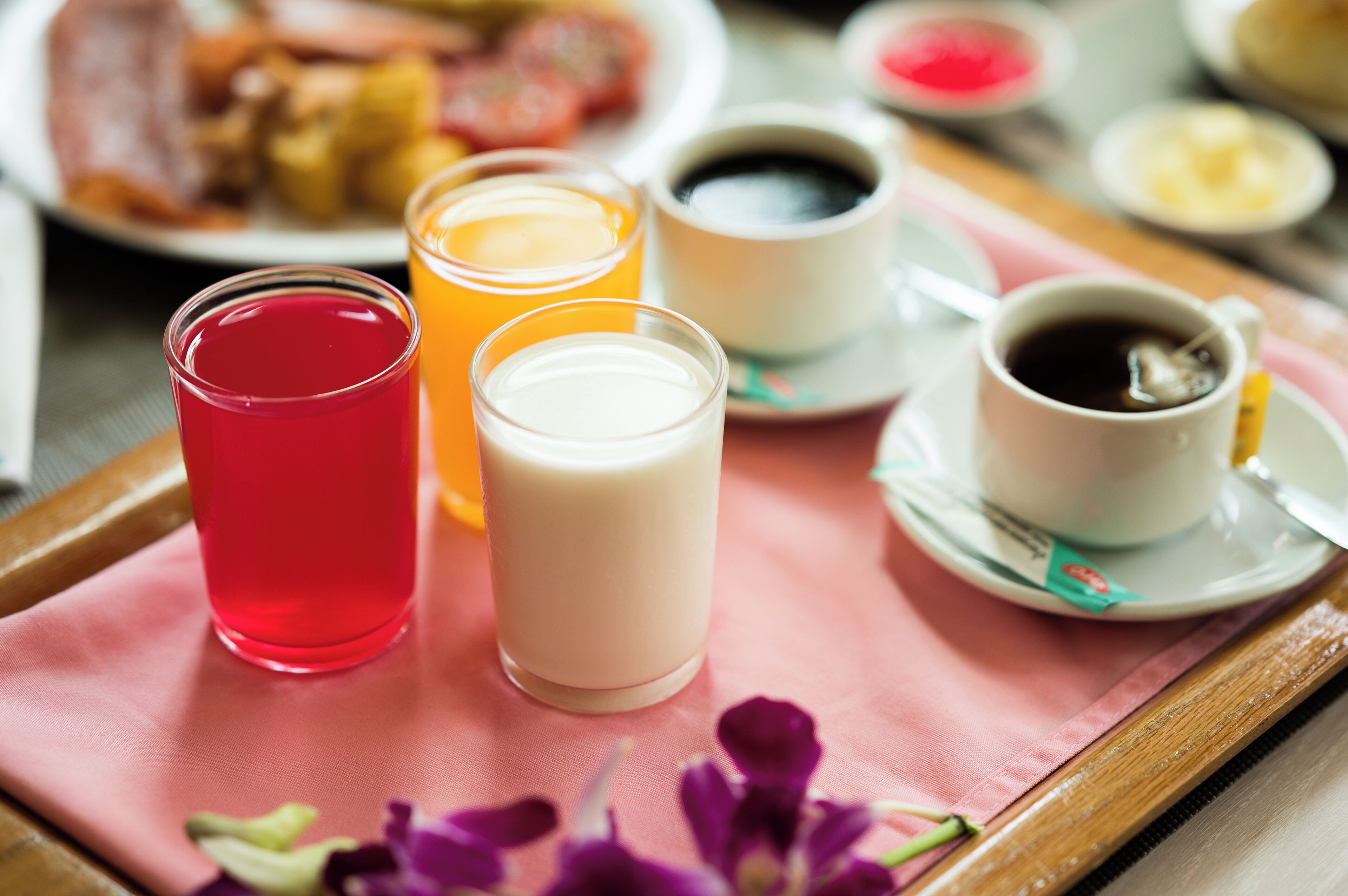 Un vassoio con tovagliolo rosa, due bicchieri e un piatto di cibo.