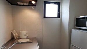 A compact kitchen with a microwave, a kettle, and a small window. - Ocean View Araha 201 (Chatan)