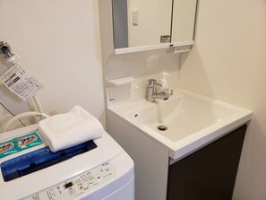 Guests can enjoy a clean and functional bathroom with a sink, mirror, and washing machine.