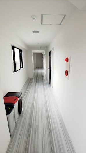 A narrow hallway with a striped floor, white walls, and a door at the end.