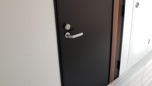 A door with a handle and a lock, a door number sign, and a white door next to it. - Ocean View Araha 201 (Chatan)