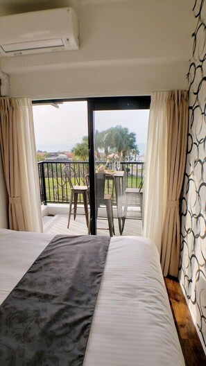 A hotel room with a bed, a balcony with a table and chairs, and a view of the outdoors. - Ocean View Araha 203 (Chatan)