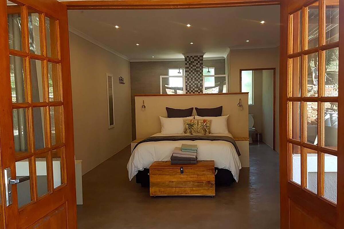 A bedroom with a large bed, a wooden chest of drawers, and a view of the bathroom through an open door.