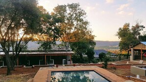 A swimming pool with a view of trees and a building in the background. - Rocky Hollow Guest Farm (Pretoria)