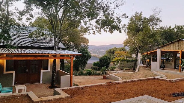 A rustic building with a covered patio, a small seating area, and a view of the landscape. - Rocky Hollow Guest Farm (Pretoria)