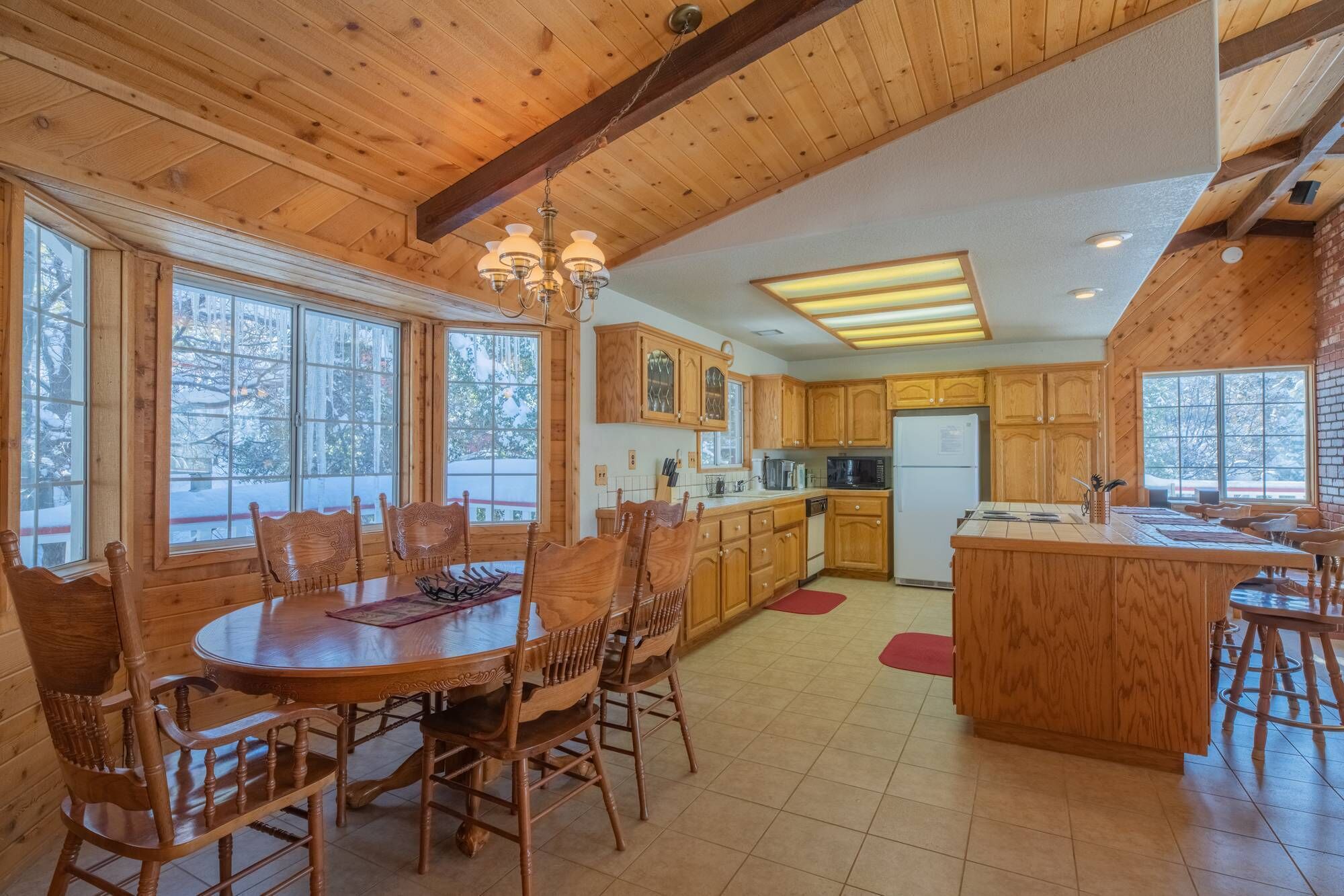 Una cocina amplia con armarios de madera, una isla central y ventanas grandes.