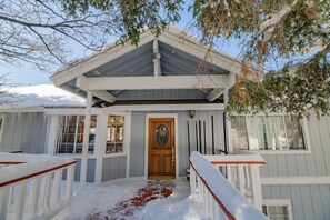 Ein zweistöckiges Haus mit einer überdachten Veranda, einer Holztür und einem verschneiten Weg.