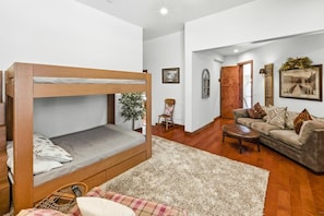 A room with a bunk bed, a sofa, a coffee table, and a chair.