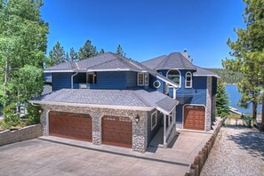 Une maison à deux étages avec un garage en pierre et une grande baie vitrée.